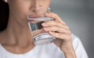 Frau trinkt Wasser aus Glas